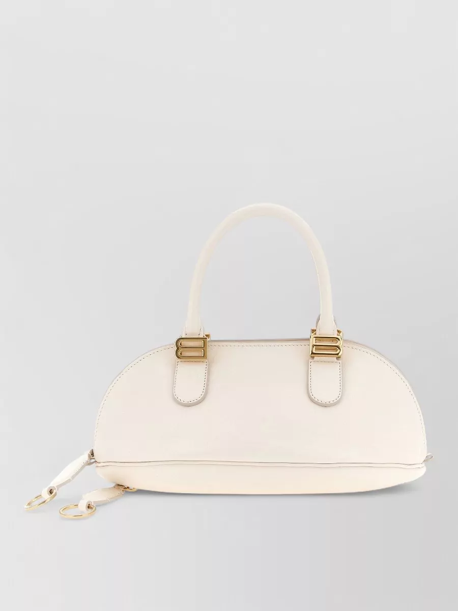 Balenciaga Mini leather shoulder bag — The Tod’s buttercream structured top‑handle sits perfectly with the minimalist suiting aesthetic, echoing the soft neutrals while adding quiet structure and a deliberately refined finish.