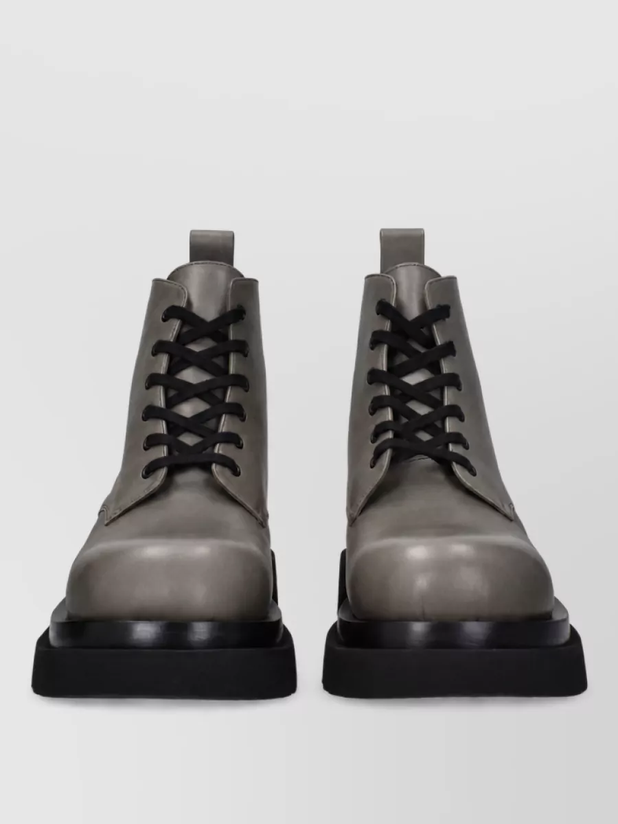 Bottega Veneta Leather derby shoes — The black lug-sole ankle boots bring the right weight under the pooling wide leg, sharpening the outfit’s formality while keeping the aesthetic minimalist and distinctly Bottega.