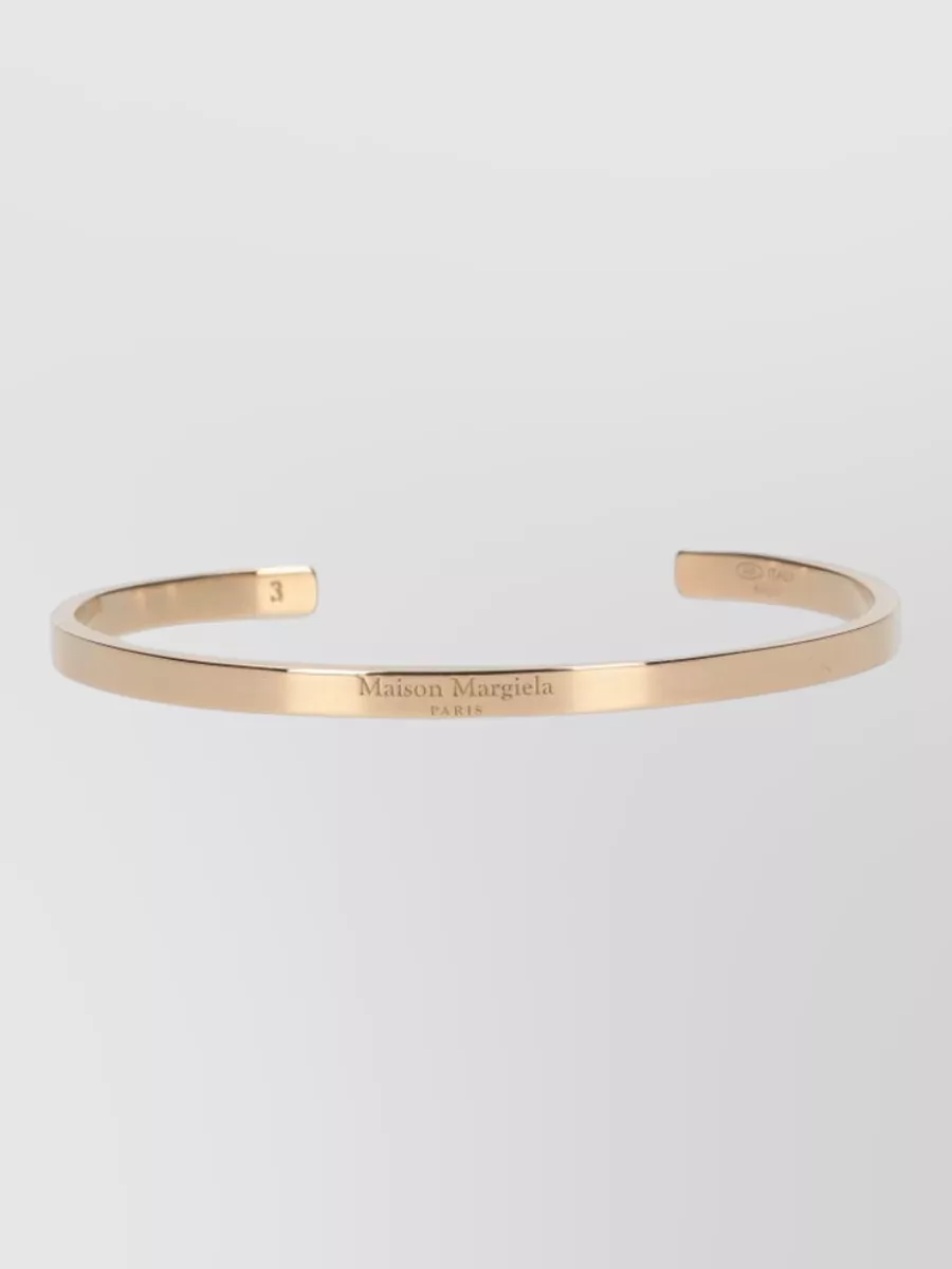 Maison Margiela Silver bracelet — The slim yellow-gold cuff feels like a quiet line of light on the wrist, adding polish and tying into the bags and shoes’ hardware without distracting from the neckline ruffles.
