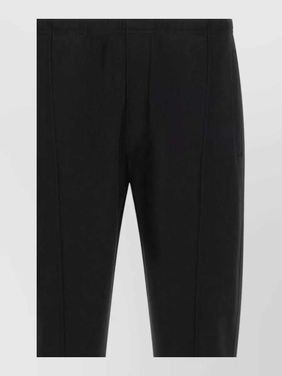 Prada Straight-leg track pants — The technical straight-leg trouser with adjustable hem mirrors the jacket’s performance aesthetic and formality while staying clean and city-ready, giving a sharper alternative to pure joggers.