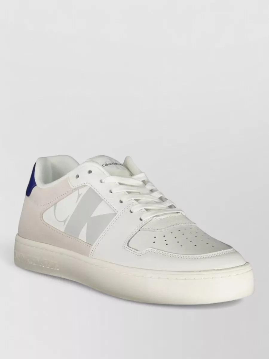 Calvin Klein Leather lace-up sneakers — The Calvin Klein off-white sneakers with cobalt detail echo the sweatshirt’s blue and keep the base light, modern and sporty, tying together top and trouser in a clean streetwear way.