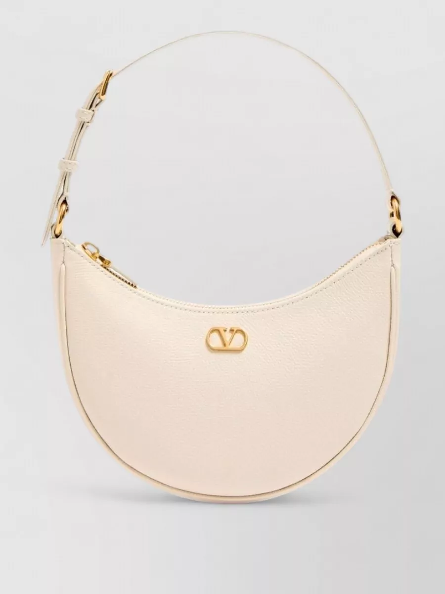 Valentino Garavani vlogo signature mini calf leather shoulder bag — The Valentino buttercream crescent shoulder bag harmonises with the dress’s soft yellow palette and refined feel, giving a clean, modern line that quietly supports the romantic narrative.