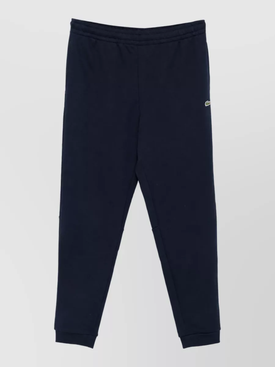 Lacoste Track pants — The Lacoste navy tapered track pant mirrors the sweatshirt’s brand, color and sporty-preppy mood, creating a clean, minimal matching set that still feels polished enough for city wear.