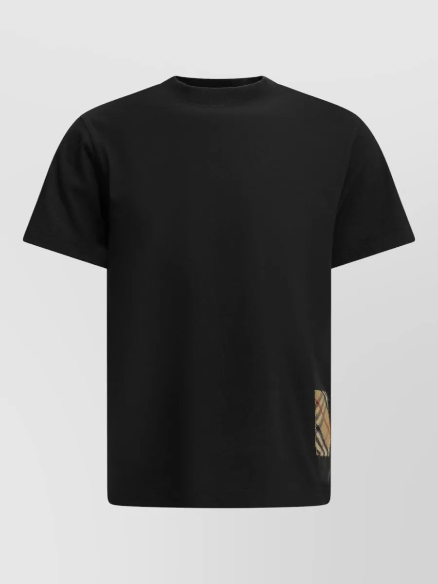Burberry Appliqué cotton crewneck t-shirt — The black Burberry tee with discreet check detail keeps the palette dark and minimal to mirror the charcoal Gucci shorts, matching their quiet logo tone and sport-leaning casual level.
