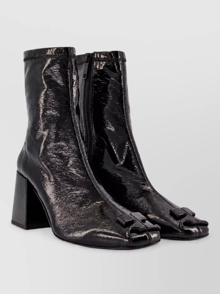 Courrèges Patent leather boots — The Courrèges glossy ankle sock boots keep the silhouette sharp and leggy, echo the patent shine of a tux-inspired mini, and balance the cropped faux-fur jacket with a modern, Y2K edge.