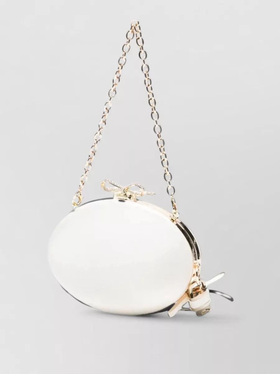 Self-Portrait diamante mini satin clutch bag — The pearl white and gold oval clutch reads as a small jewel against the black-and-ivory outfit, reinforcing the romantic party mood at a similarly refined price tier.
