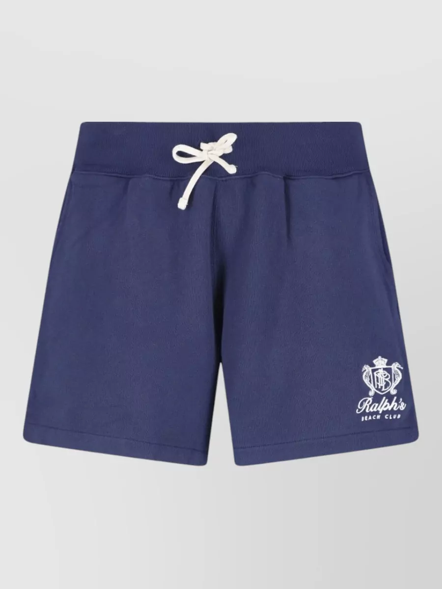 Polo Ralph Lauren Straight deck shorts — The clean navy deck short with red pony mirrors the tee’s collegiate surf-club energy and palette while keeping the silhouette regular and polished enough for city or beach.