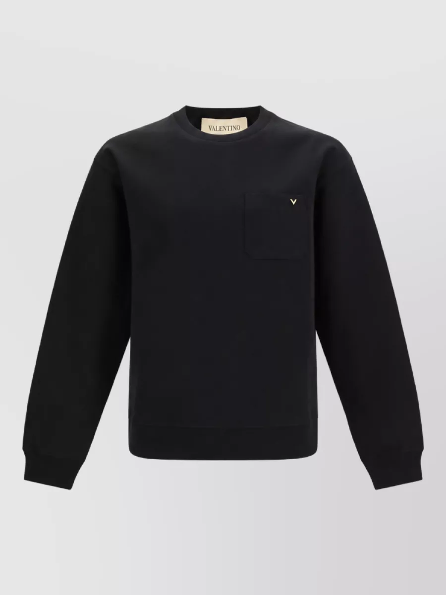 Valentino Cotton-blend crew-neck sweatshirt — The black long-sleeve tee with subtle gold V keeps the palette seamless with the track pant while matching its quiet-luxury, slightly polished athleisure mood.