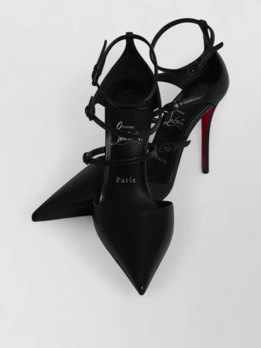 Christian Louboutin Leather strappy pumps — The black Christian Louboutin pointed-toe strappy pump mirrors the dress’s drama and tailoring while keeping to a black‑and‑red palette that feels sharp, sensual and seasonally light.