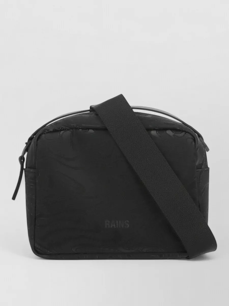 Rains Waterproof shoulder bag — The compact black Rains crossbody ties back to the jacket’s utilitarian hardware, matches the dark base of dress and sneakers, and keeps the overall silhouette clean and functional.
