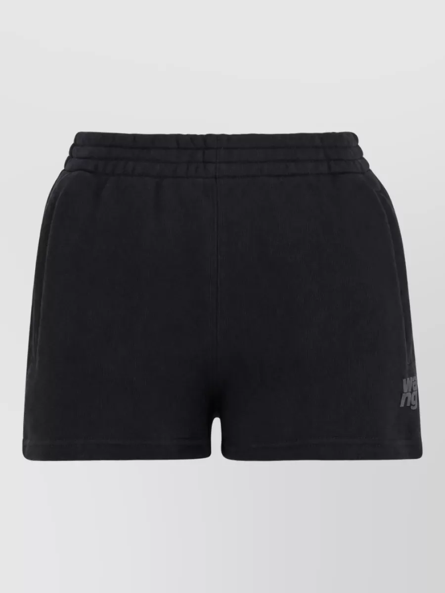 Alexander Wang Logo-embossed shorts — The black Alexander Wang logo shorts mirror the sporty, off-duty mood and cropped proportion of the hoodie while keeping the palette graphic and cohesive within the same brand universe.