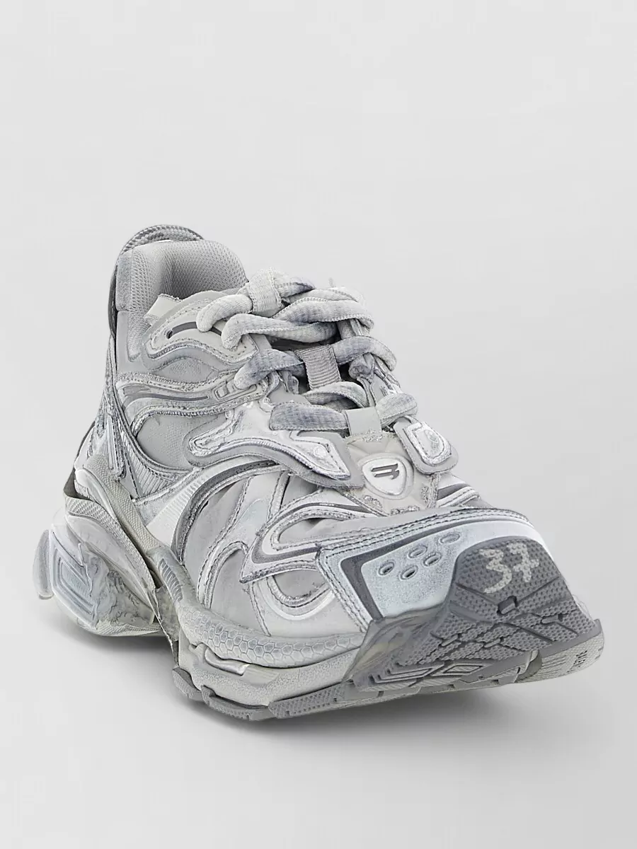 Balenciaga Runner 2.0 low-top sneakers — The chunky runner in layered light greys and off-white ties into the tee’s heather base and the denim’s fade, giving a technical street edge that suits the relaxed wide leg.