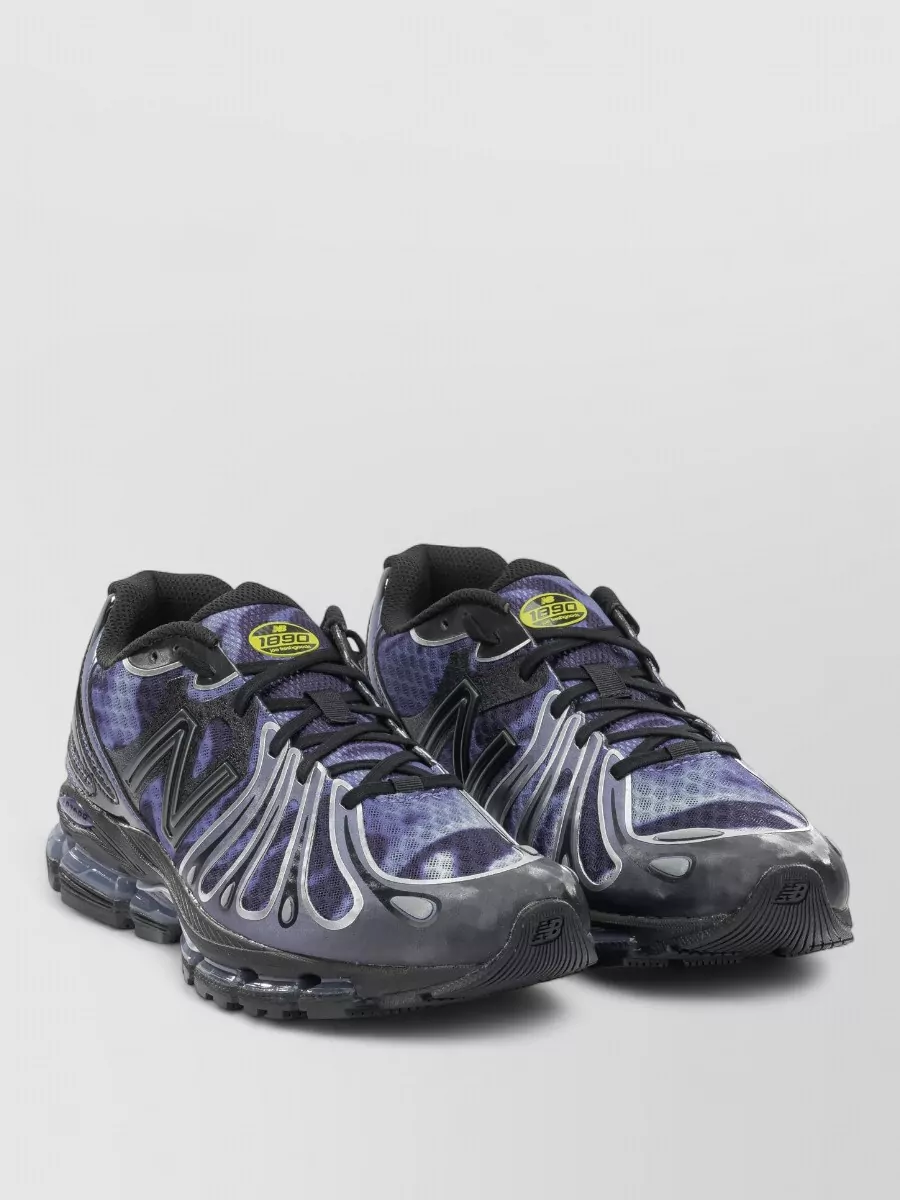 New Balance Synthetic low-top sneakers — The ink navy New Balance runner keeps the palette dark and tonal with the pants while leaning into a technical, sporty profile that suits the track silhouette.
