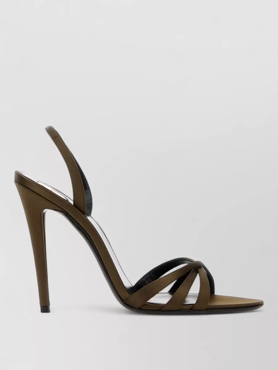 Saint Laurent Satin sandals — The olive-brown strappy stiletto sandal keeps the look light and elongated with the wide-leg jumpsuit, harmonising with the camel palette while reading evening-appropriate and quietly sensual.