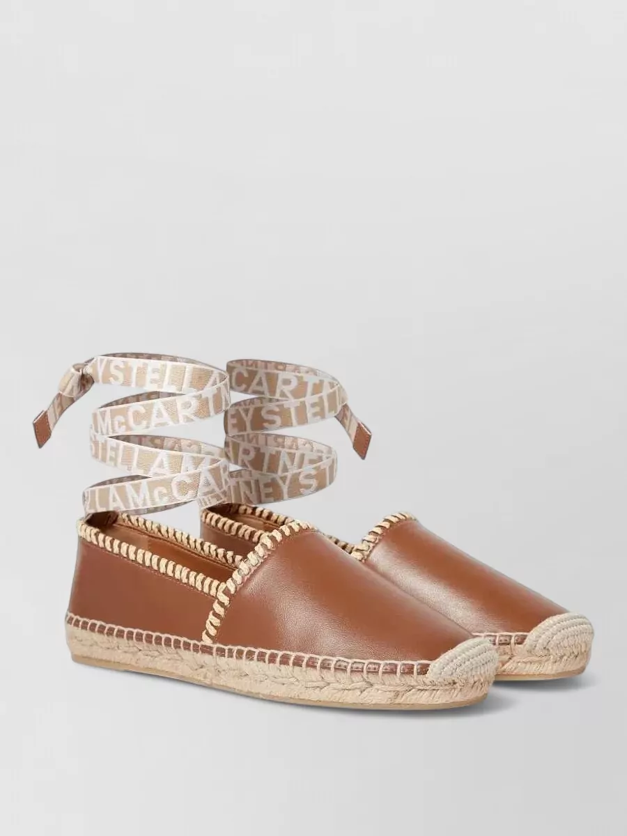 Stella Mccartney Whipstitched ankle-tie espadrilles — The tan ankle-wrap espadrilles sit perfectly with the ivory-and-red blouse and white skirt, keeping the palette warm and romantic while their ties echo the artisanal detailing without adding visual weight.