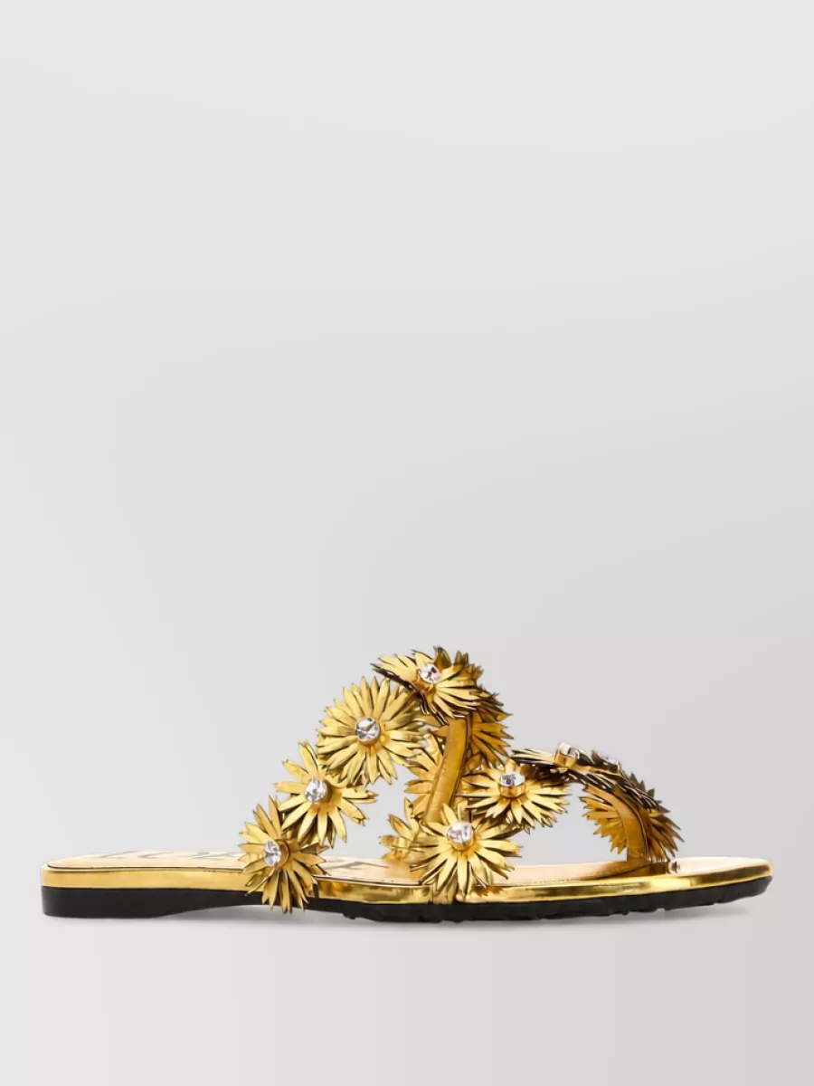 Loewe Paula's Ibiza Leather slides — The metallic gold flat slides feel dressy enough for terrace cocktails but keep the vibe relaxed and bohemian, and their warm shine complements the skirt’s ivory without fighting its texture.