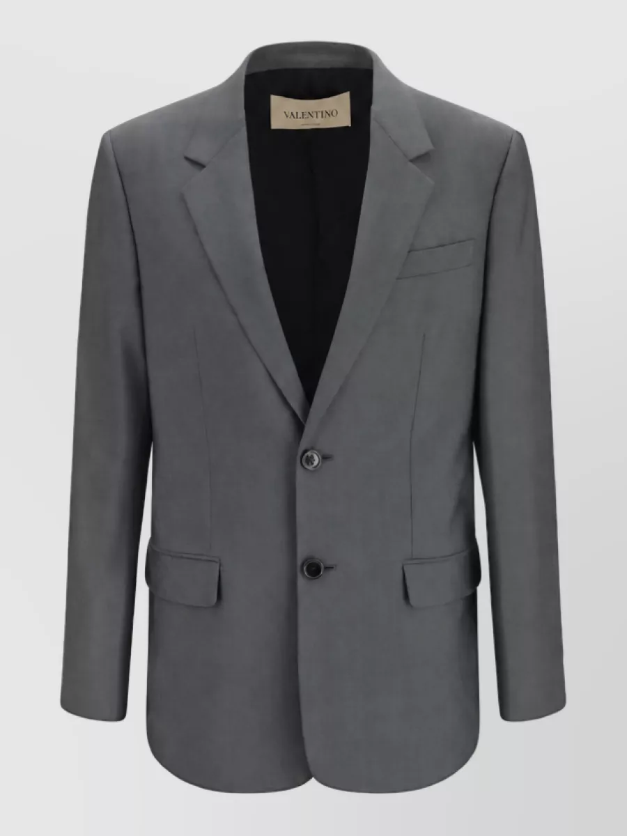Valentino Garavani Wool single breasted suit — The Valentino Garavani charcoal blazer in A completes a cohesive quiet-luxury suit with the pleated charcoal trouser, matching formality, palette and tailoring for a sharp high-rise wide-leg silhouette.