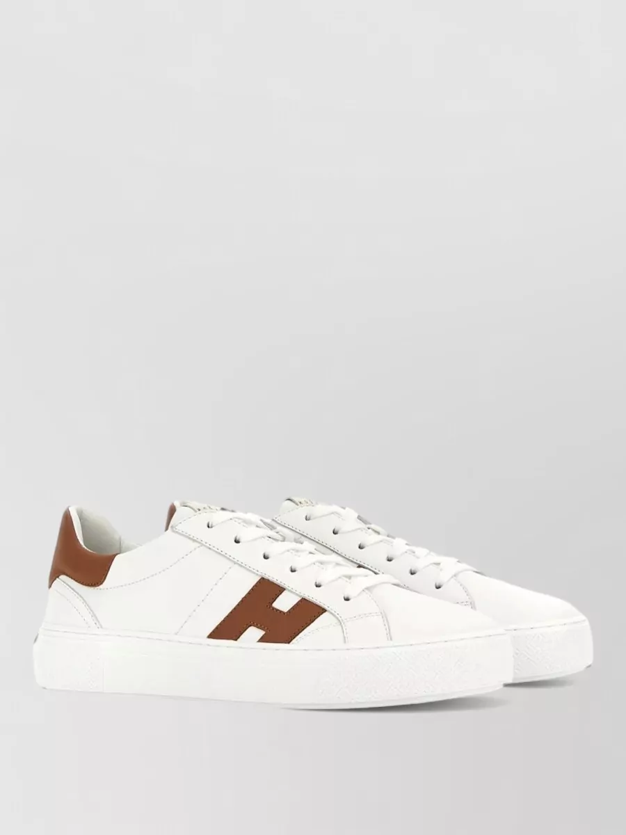 Hogan Leather lace-up sneakers — J’s crisp white leather and tan accent read classic and sporty, grounding the grey set in a way that feels clean, versatile and in line with the preppy mood.