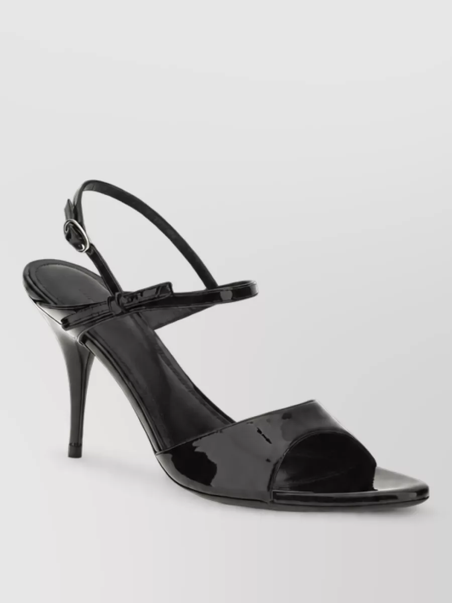 Balenciaga Leather stiletto sandals — The black patent slingback keeps the line clean and leg-lengthening, matching the dress’s refined evening formality without adding competing ornament at the hem lace.
