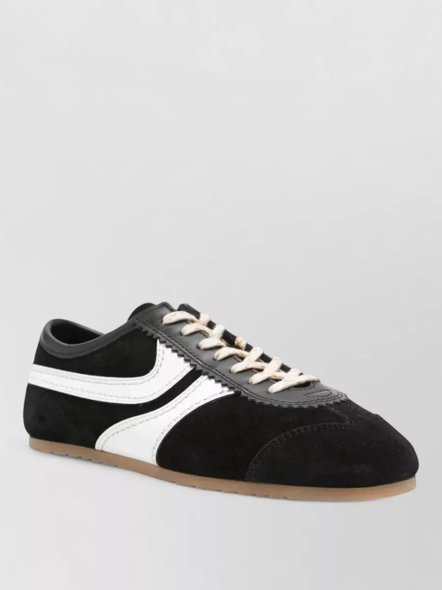 Dries Van Noten Leather low-top sneakers — The Dries Van Noten retro track sneaker keeps the outfit grounded in black with subtle off‑white and gum accents that echo the shorts’ bone detailing while staying refined and low profile.