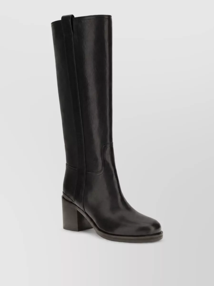 Brunello Cucinelli Calf leather high heel boots — The Brunello Cucinelli black knee-high block-heel boot grounds the lace mini and red coat with clean, tailored authority while keeping the leg line long and winter-appropriate.