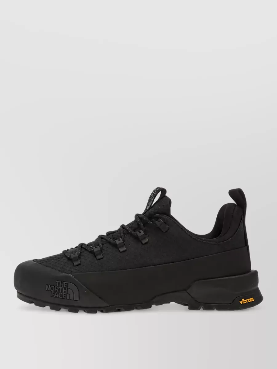 The North Face Textile low-top sneakers — The black New Balance trail runner is technical, low-profile and all-black, tying into the pants and reinforcing the urban-outdoor performance story without overpowering the K-way pieces.