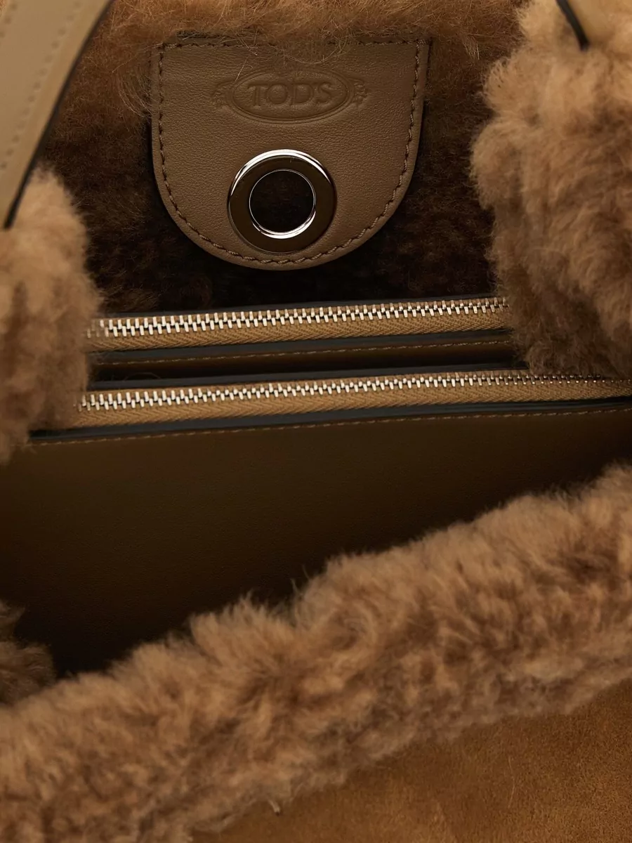 Tod's bucket small leather shoulder bag — The Chloé dark chocolate faux-fur tote echoes the coat’s plush texture while grounding the camel and taupe palette, keeping the outfit luxe and practical for day-to-dinner wear.