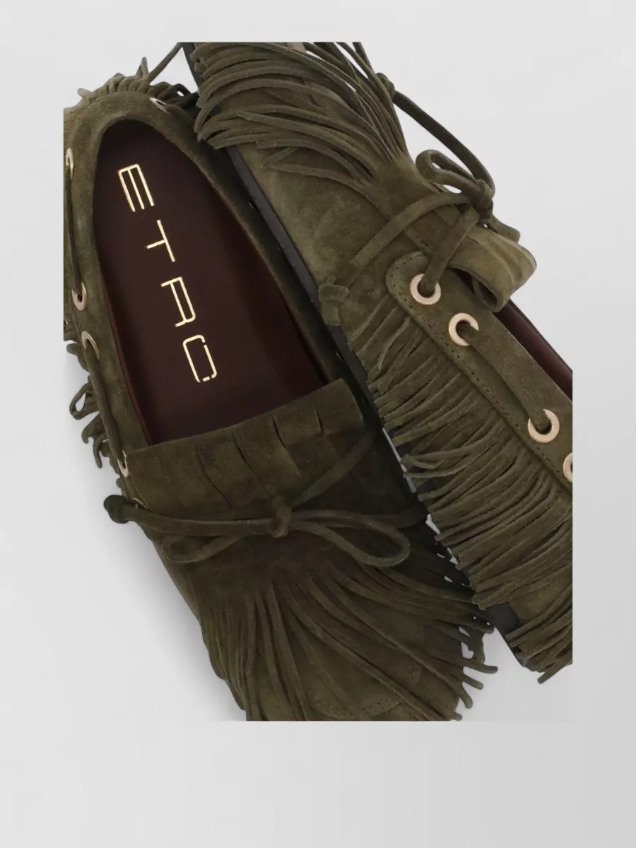 Etro Suede moccasins — The olive Etro fringed moccasin echoes the poncho’s bohemian fringe and earthy tones while staying flat and relaxed enough to suit the resort-to-city mood of the knit maxi.
