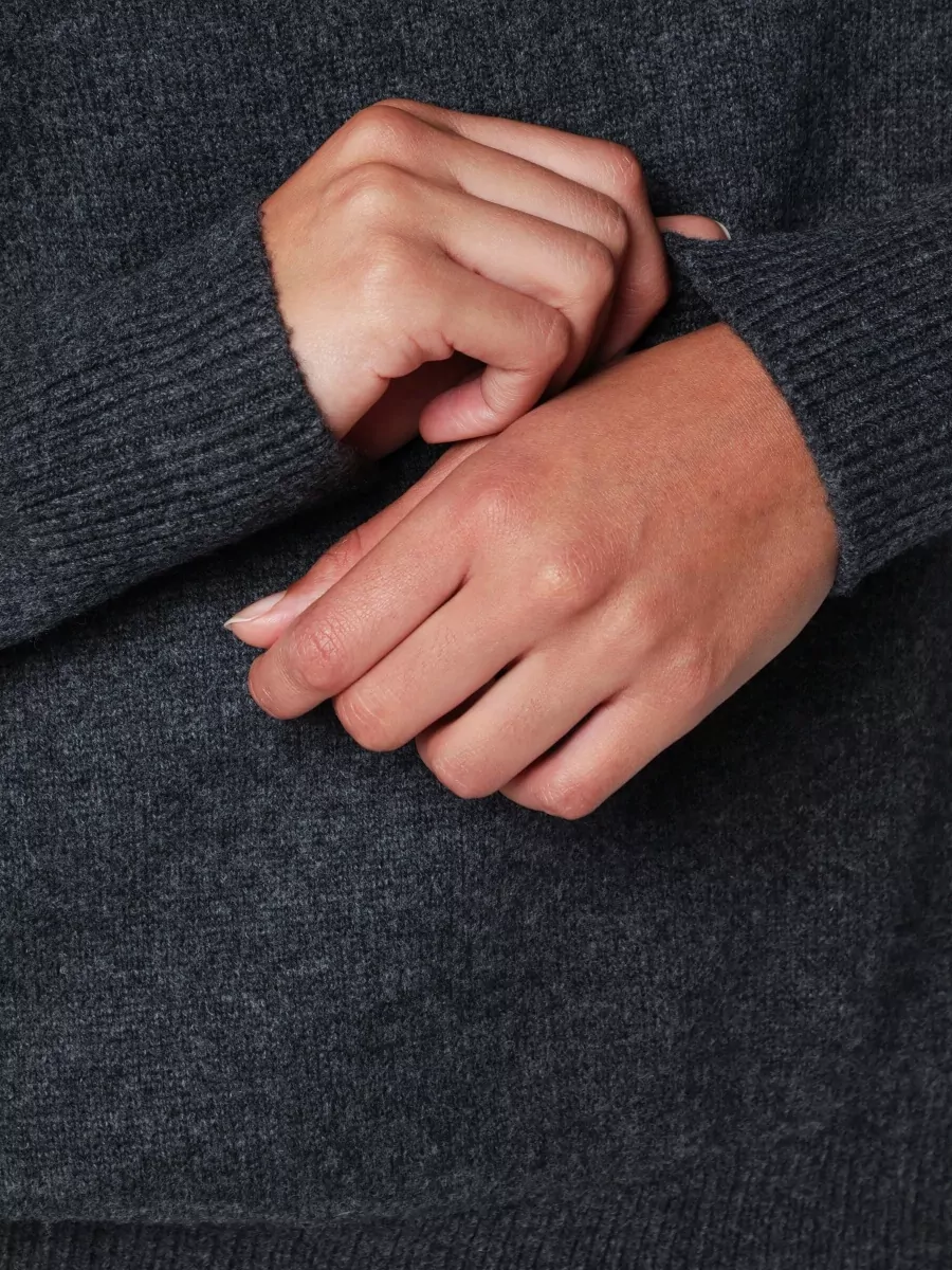 Dunst Jumper — The relaxed charcoal V-neck mirrors the jacket’s washed black tone and slouchy volume, giving a soft, low-contrast layer that keeps the mood urban and understated.