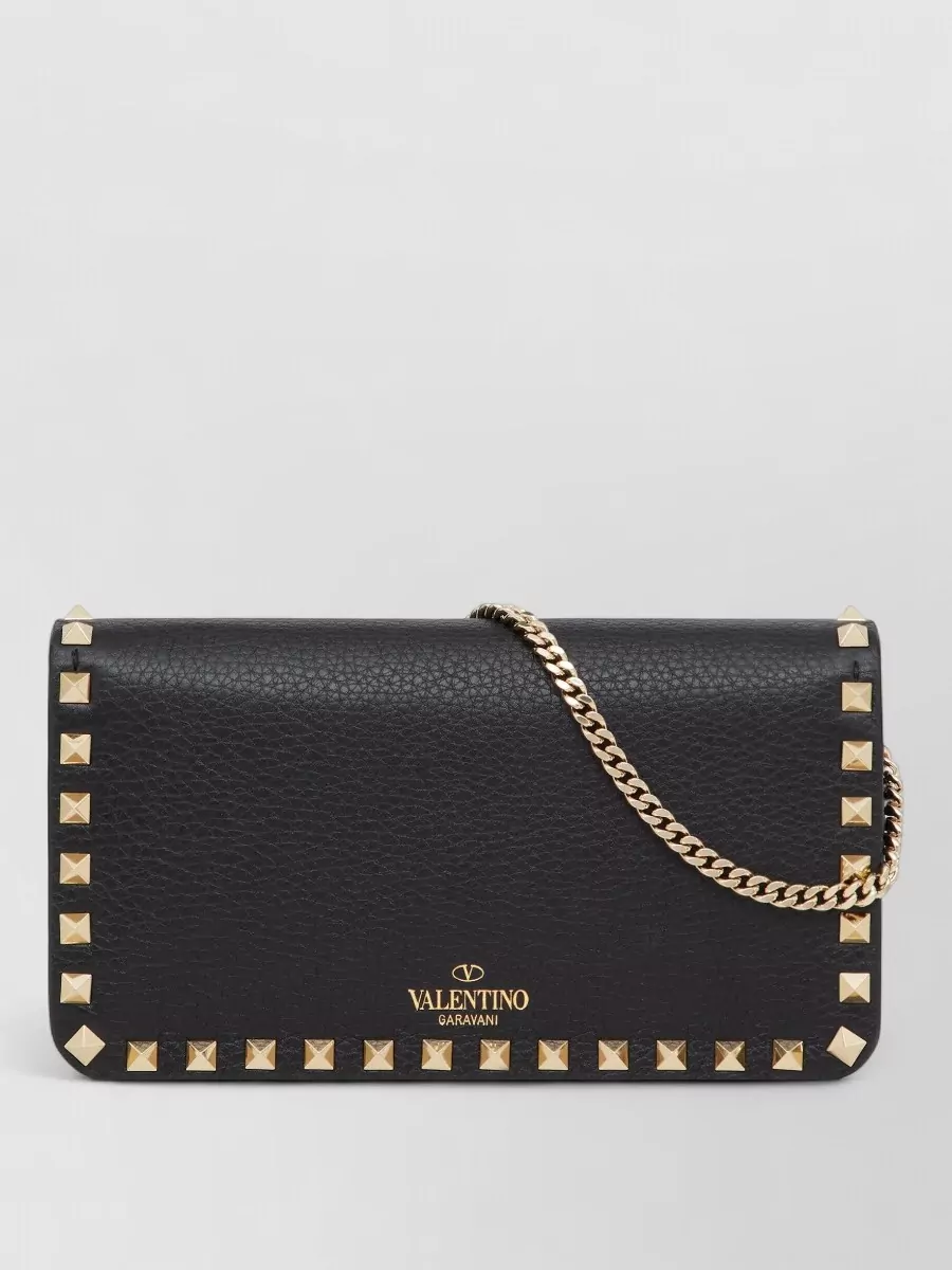 Valentino Garavani rockstud spike leather chain wallet — The compact Valentino Rockstud flap with gold hardware echoes the sandals’ studs and black leather while staying evening-appropriate and proportionate to the slim slip dress.