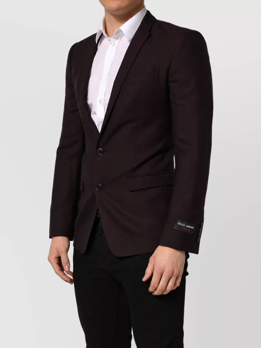 Dolce&Gabbana Virgin wool single breasted suit — K’s slim, plain black single-breasted tailoring matches the coat’s sharp, crest-detailed formality without adding extra pattern or color, keeping the layered suiting clean and regal.