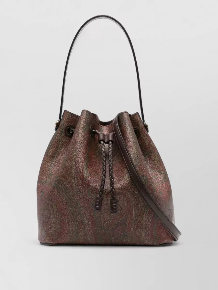 Etro saturno medium leather bucket bag — The Etro paisley bucket in deep browns and muted burgundy harmonizes with the trouser’s earthy chevrons and the wooden-effect mules, keeping the focus rich and bohemian rather than logo-driven.