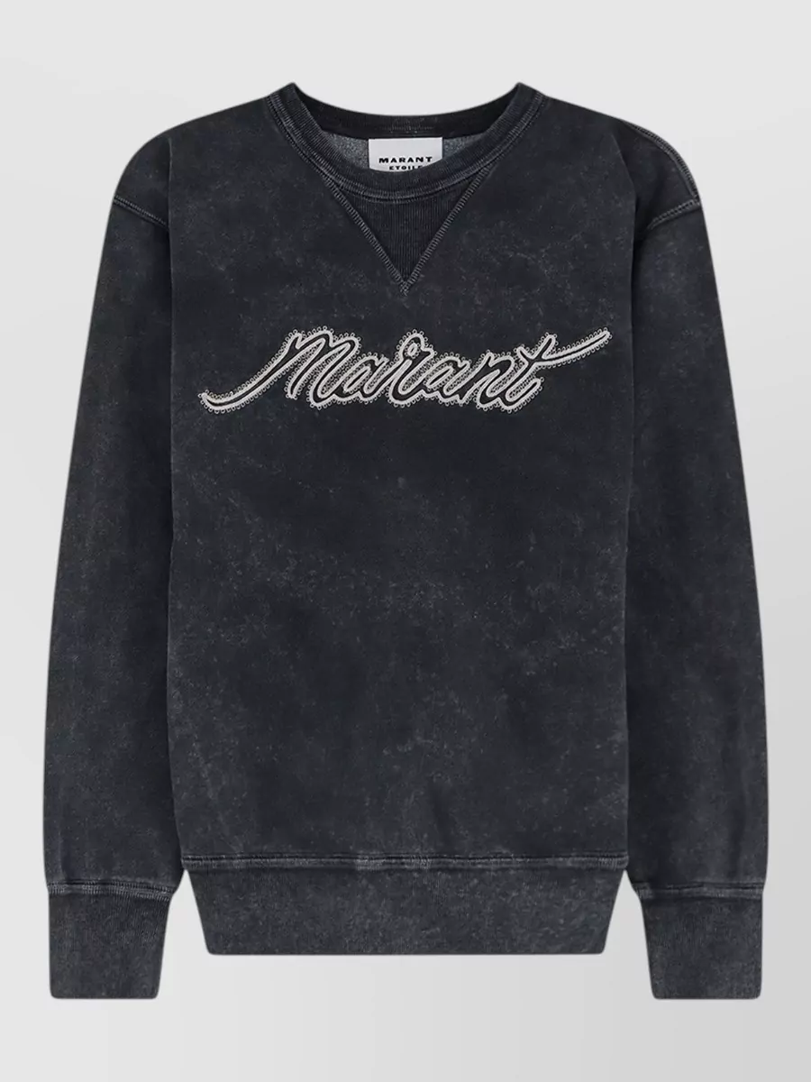 Isabel Marant Etoile Ribbed long-sleeve sweatshirt — The washed-black logo sweatshirt mirrors the jean’s tone and streetwear edge, creating a monochrome base that feels cohesive and relaxed while keeping the proportions casual with the wide leg.