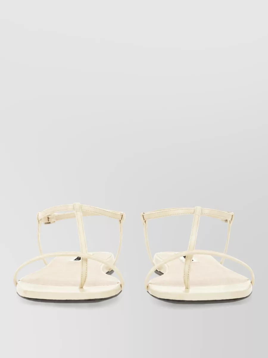 Jil Sander Leather sandals — The Jil Sander flat strappy sandal is barely there in profile and color, echoing the sweater’s lightness while keeping the outfit refined and summer-focused.