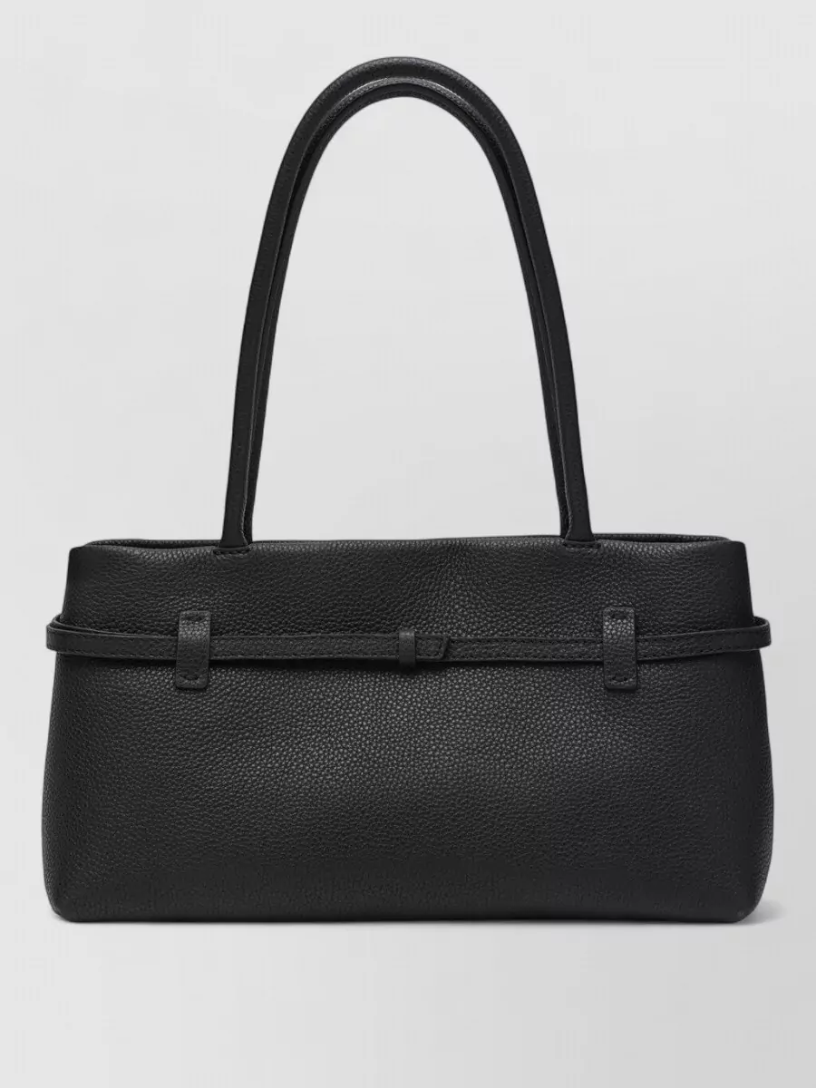 Manu Atelier cylinder shoulder bag — The elongated black shoulder bag with subtle structure complements the tailored column of tank and trouser, reading polished and discreet for both day and evening in the same quiet-luxury language.