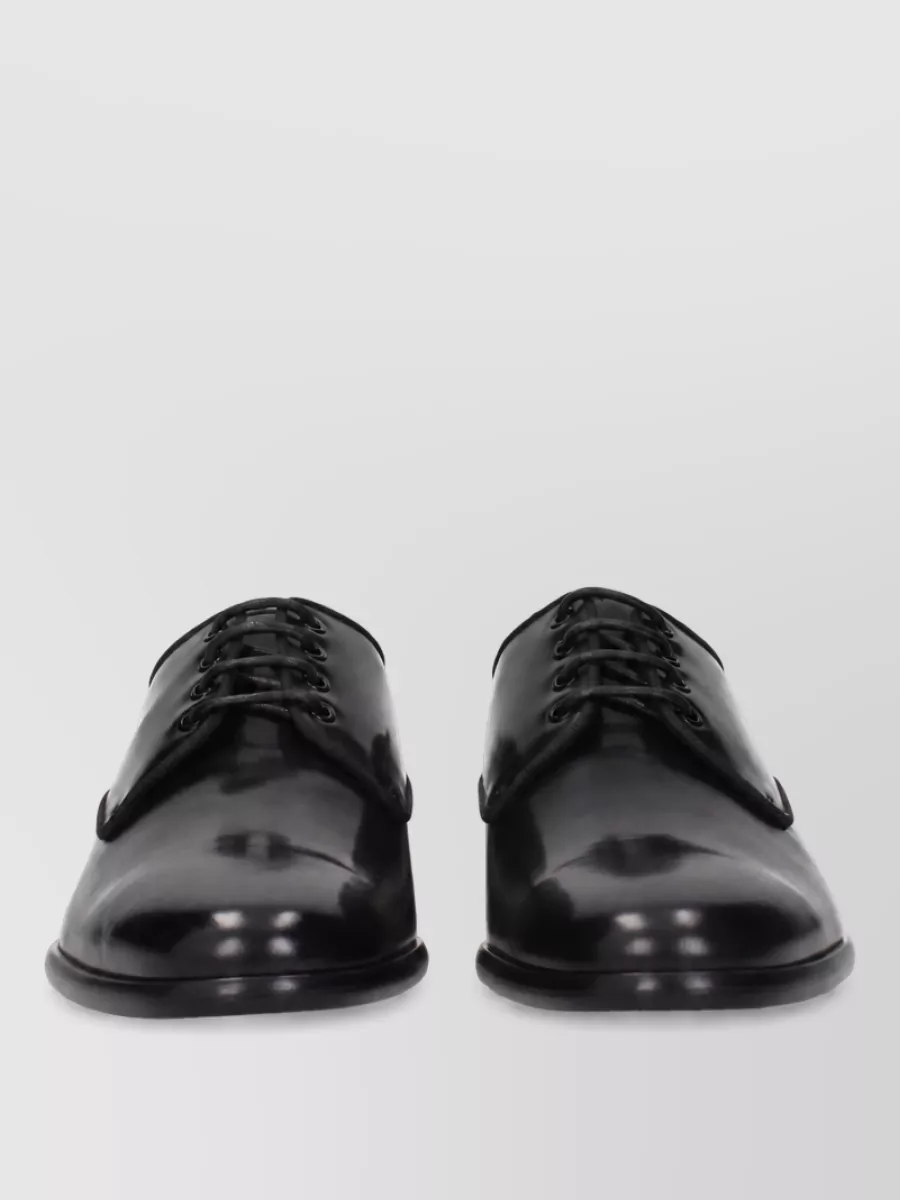 Dolce&Gabbana Leather derby shoes — The sleek black oxford reinforces the quiet, tailored attitude and anchors the midi length with an androgynous edge that suits the tee-and-wrap-skirt pairing.