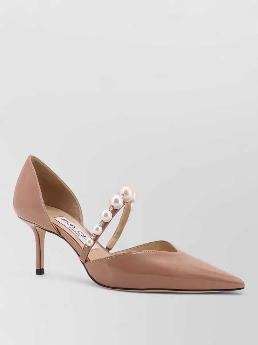 Jimmy Choo Leather embellished pumps — The nude-rose Jimmy Choo pump keeps the focus on the Dolce&Gabbana dress while echoing its pearls-and-roses romance in a polished, mid-heel silhouette that suits daytime garden-party formality.