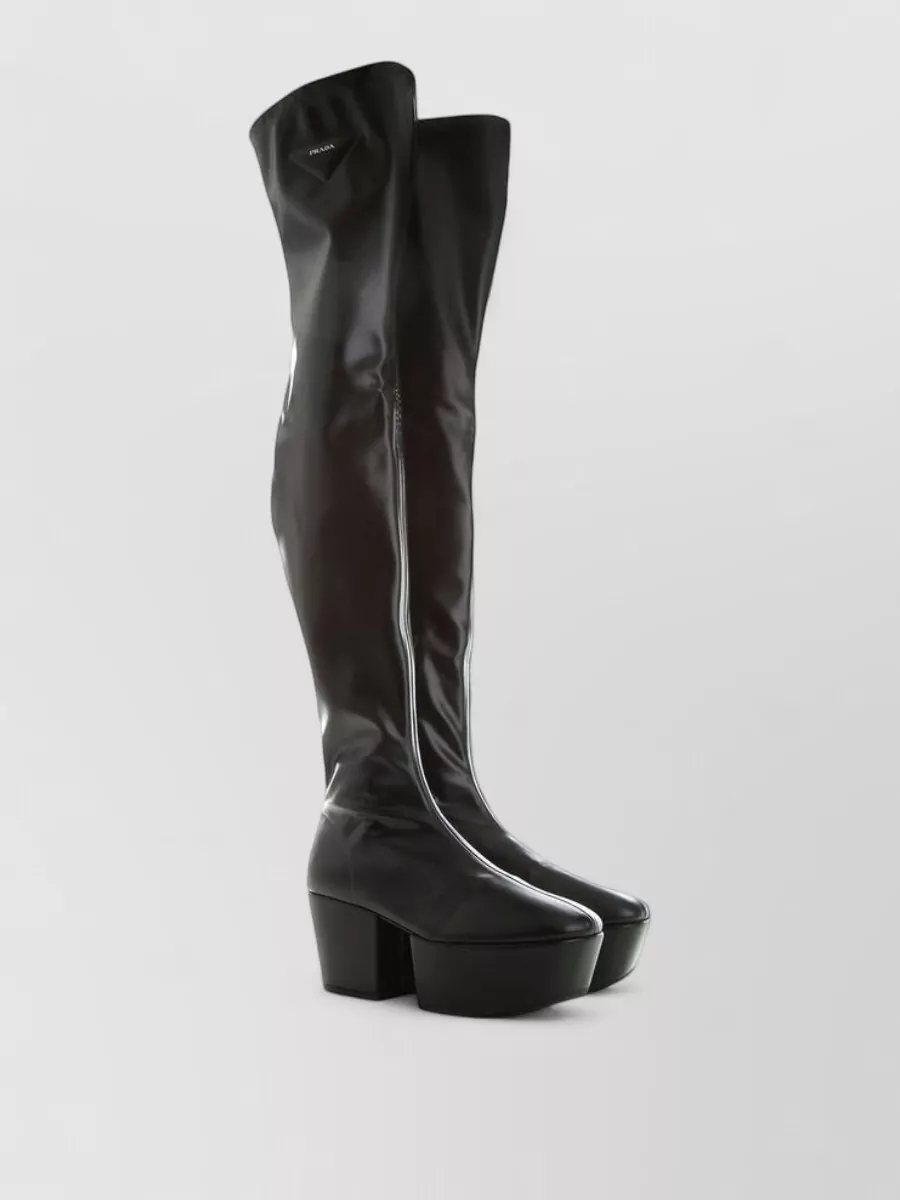 Prada Calfskin over the knee boots — The Prada over-the-knee platform boot extends the black column and amplifies the armored, futuristic mood of the Rick jacket while keeping the silhouette long and nightlife-focused.