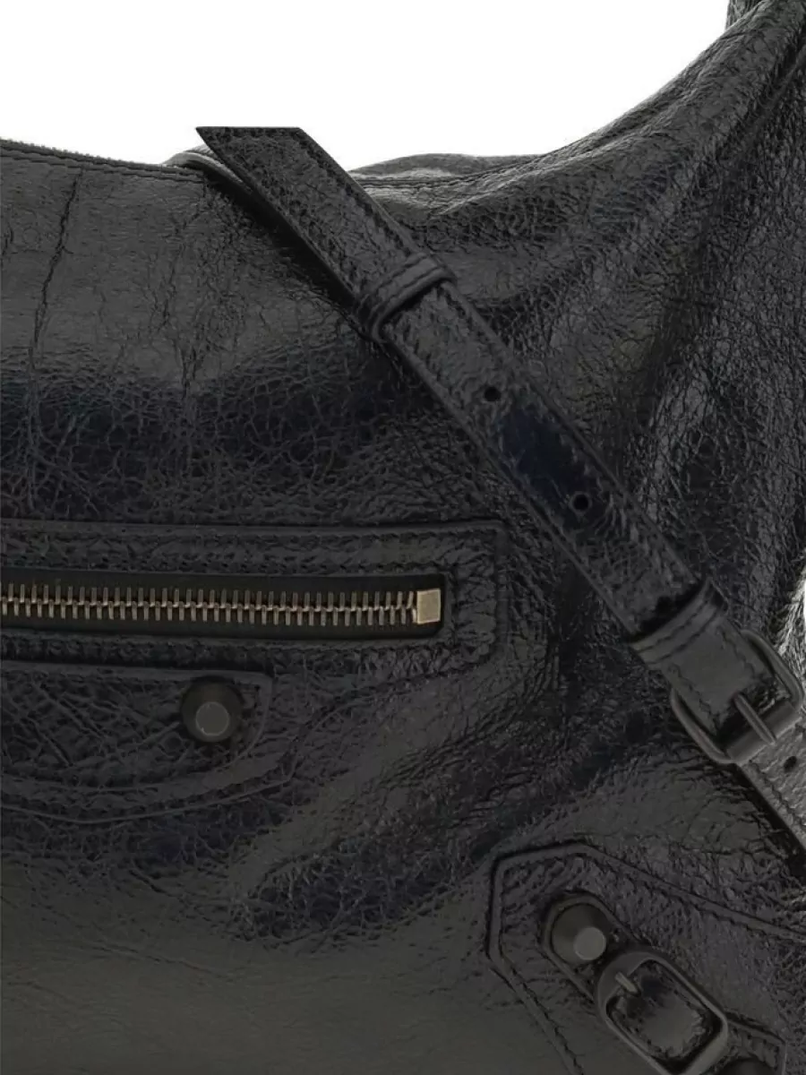 Balenciaga Aries lamb leather shoulder bag — The soft black shoulder bag in crinkled leather mirrors the jacket’s and boots’ lived-in attitude, keeps to the dark palette, and adds that signature Balenciaga slouch without competing with the sculptural denim.