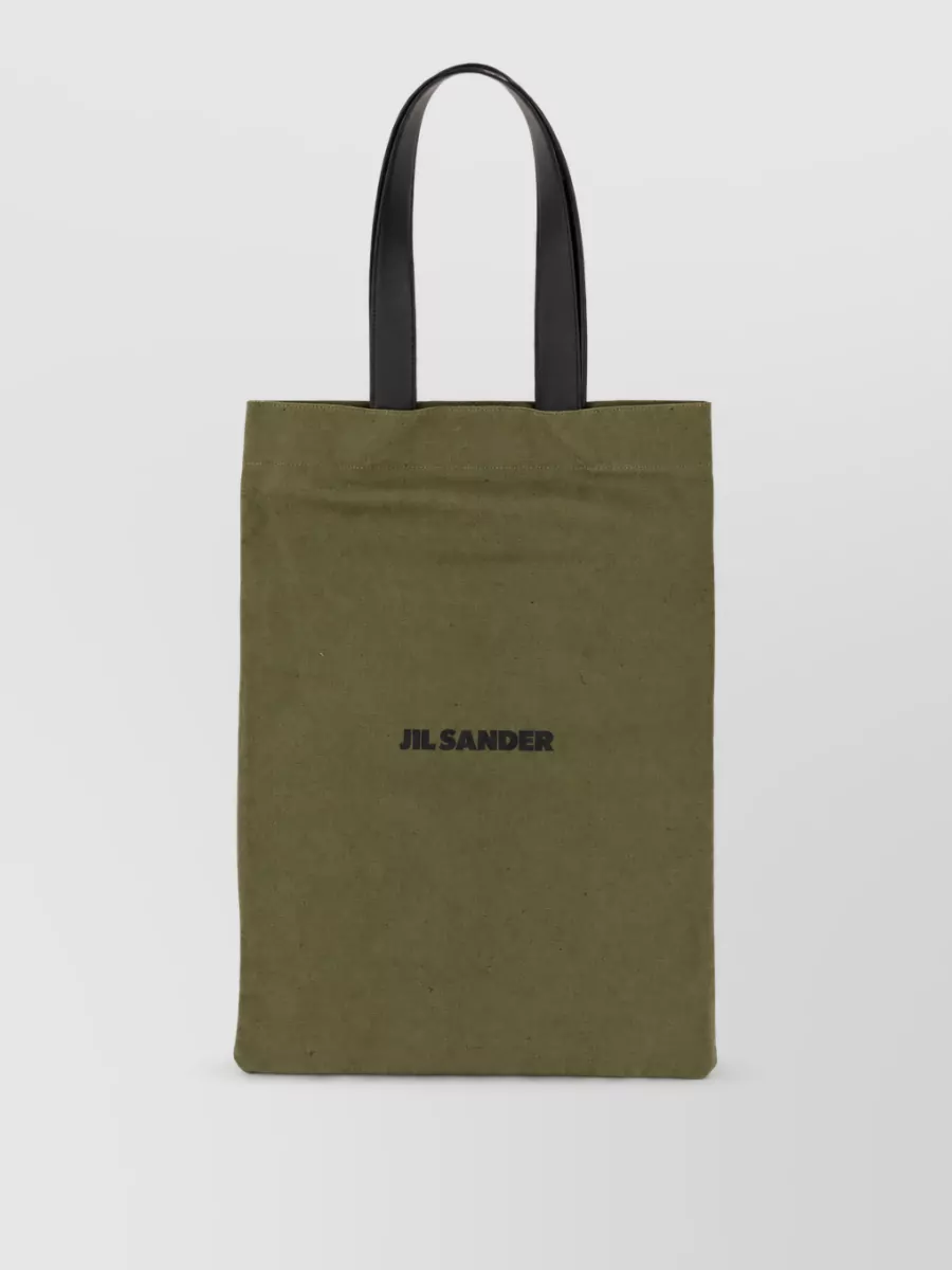 Jil Sander Canvas shoulder bag — The slim chocolate Celine crossbody ties into the earthy taupe of the polo, keeps the silhouette clean and hands-free, and matches the understated, high-end mood of the outfit.
