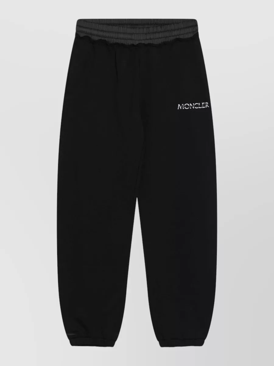 Moncler Loungewear top — The black tapered Moncler jogger mirrors the sweatshirt’s relaxed sport energy and price tier, creating a sleek monochrome set that reads intentional rather than pyjama.