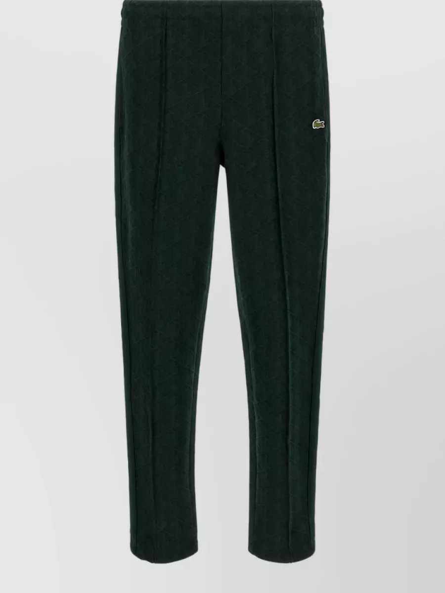 Lacoste Straight-leg trousers — The deep forest-green Lacoste track pant lines up tonally with the Autry jacket, keeping the outfit cohesive and FW-appropriate while the straight leg prevents the set from feeling too slouchy.