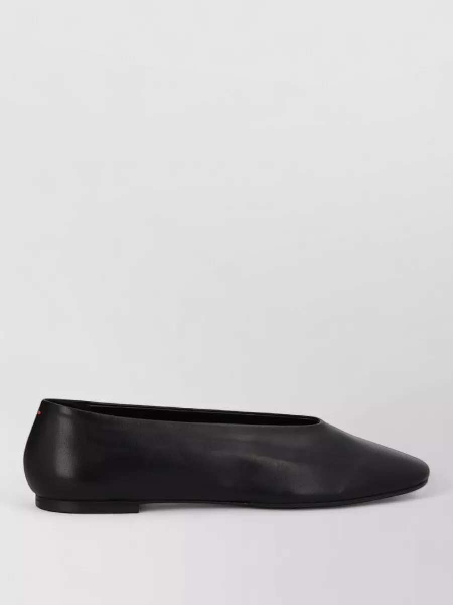 Aeyde Kirsten ballet flats square toe — The Studio Nicholson ivory flat slingbacks keep the outfit grounded, airy and utilitarian, while the soft contrast to the black dress stays within a calm minimalist palette.