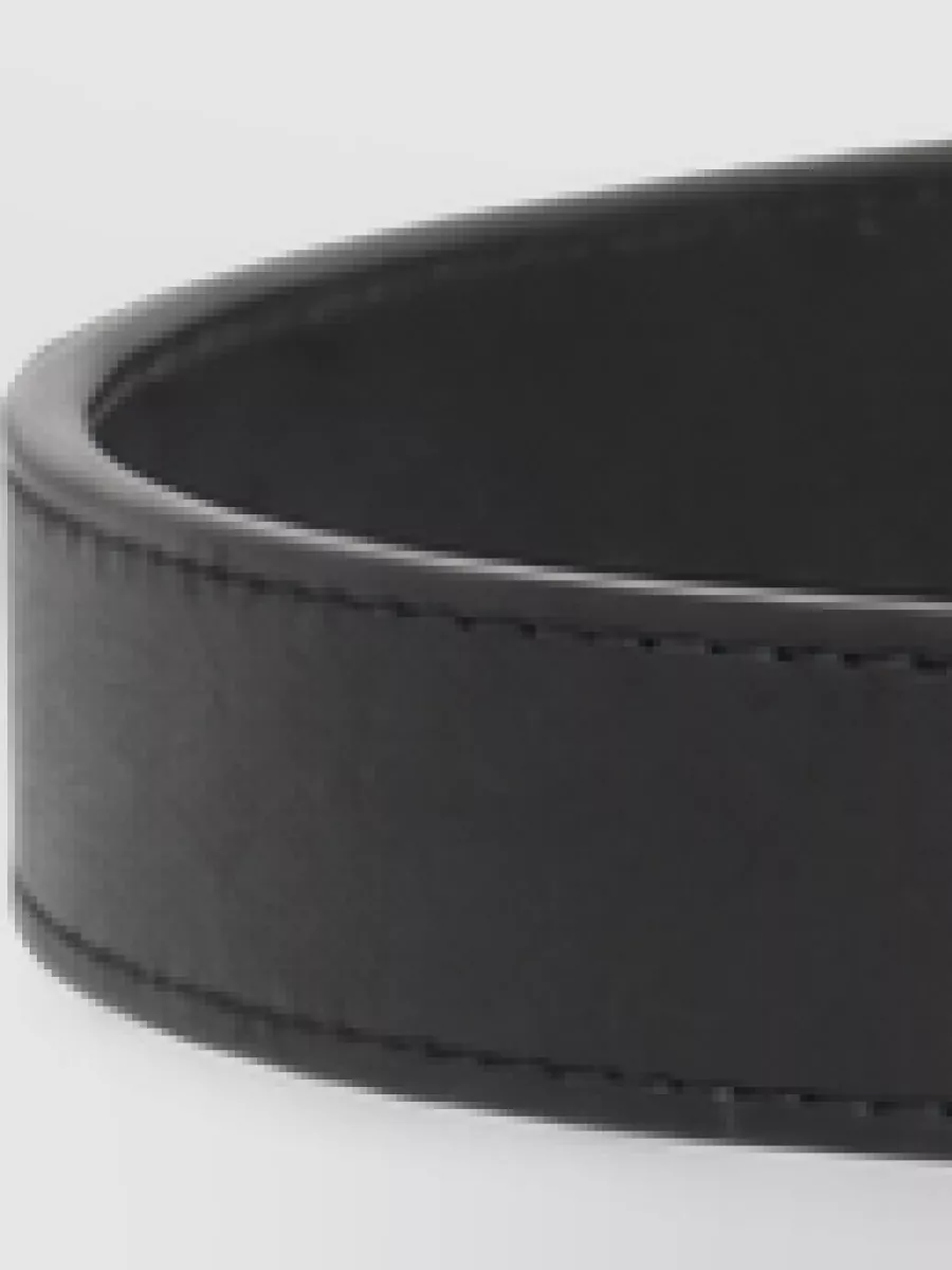 Valentino Garavani Leather belt — The slim black belt with gold VLogo can subtly define the trouser waist, tying in the gold accents from the bag and boots while keeping the overall look clean and restrained.