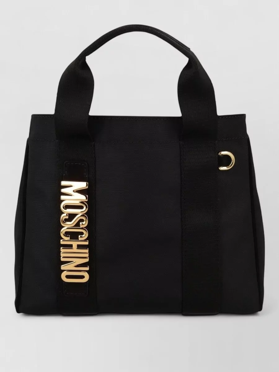 Moschino Tote bag — The black hobo with bold gold logo complements the playful branding on the tee and shorts, keeps the palette monochrome, and feels casual yet polished on the shoulder.