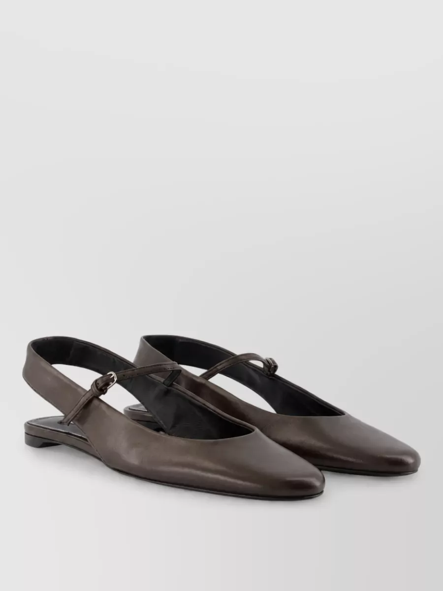 Totême Leather mules — The Totême flat pointed slingbacks in deep taupe brown stay in the neutral family yet subtly ground the sandy palette, their low profile keeping the outfit relaxed but office-appropriate.