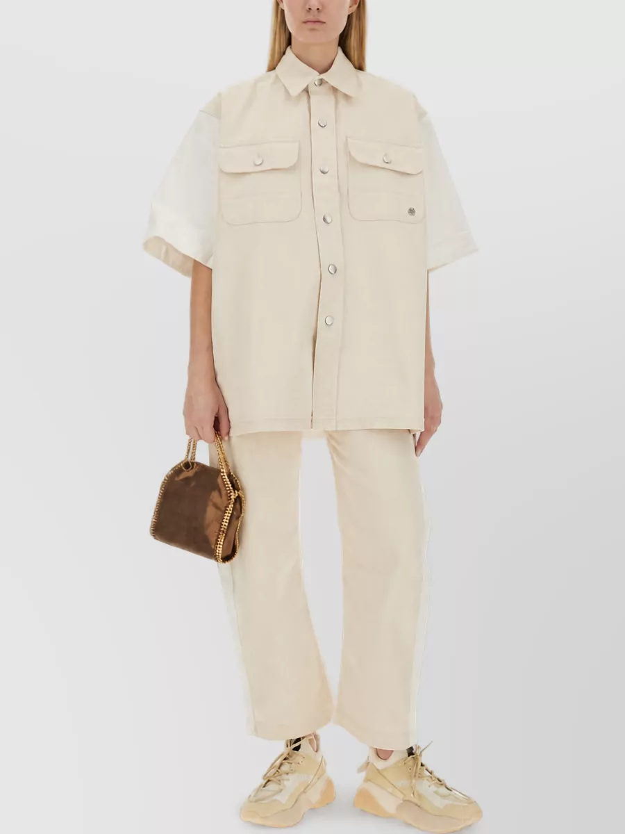 Stella Mccartney Denim shirt — The creamy short-sleeve utility shirt echoes the trouser’s workwear mood and warm neutrals, giving a modern, boxy proportion that sits cleanly over the straight-leg cargo silhouette.