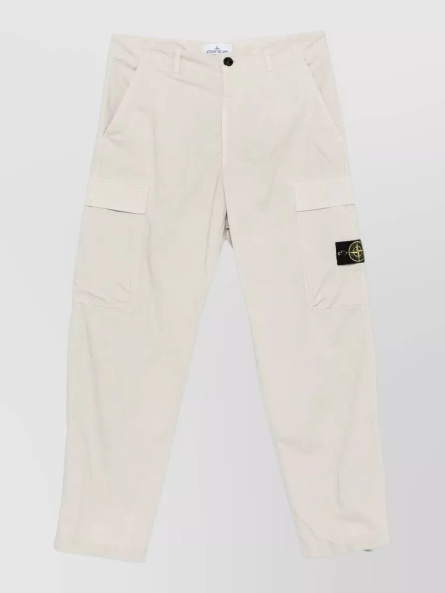 Stone Island Cargo shorts — The light beige cargo shorts keep the palette soft against the pastel yellow tee, echo the street-utility vibe, and their clean, regular fit matches the tee’s relaxed but not slouchy proportion.