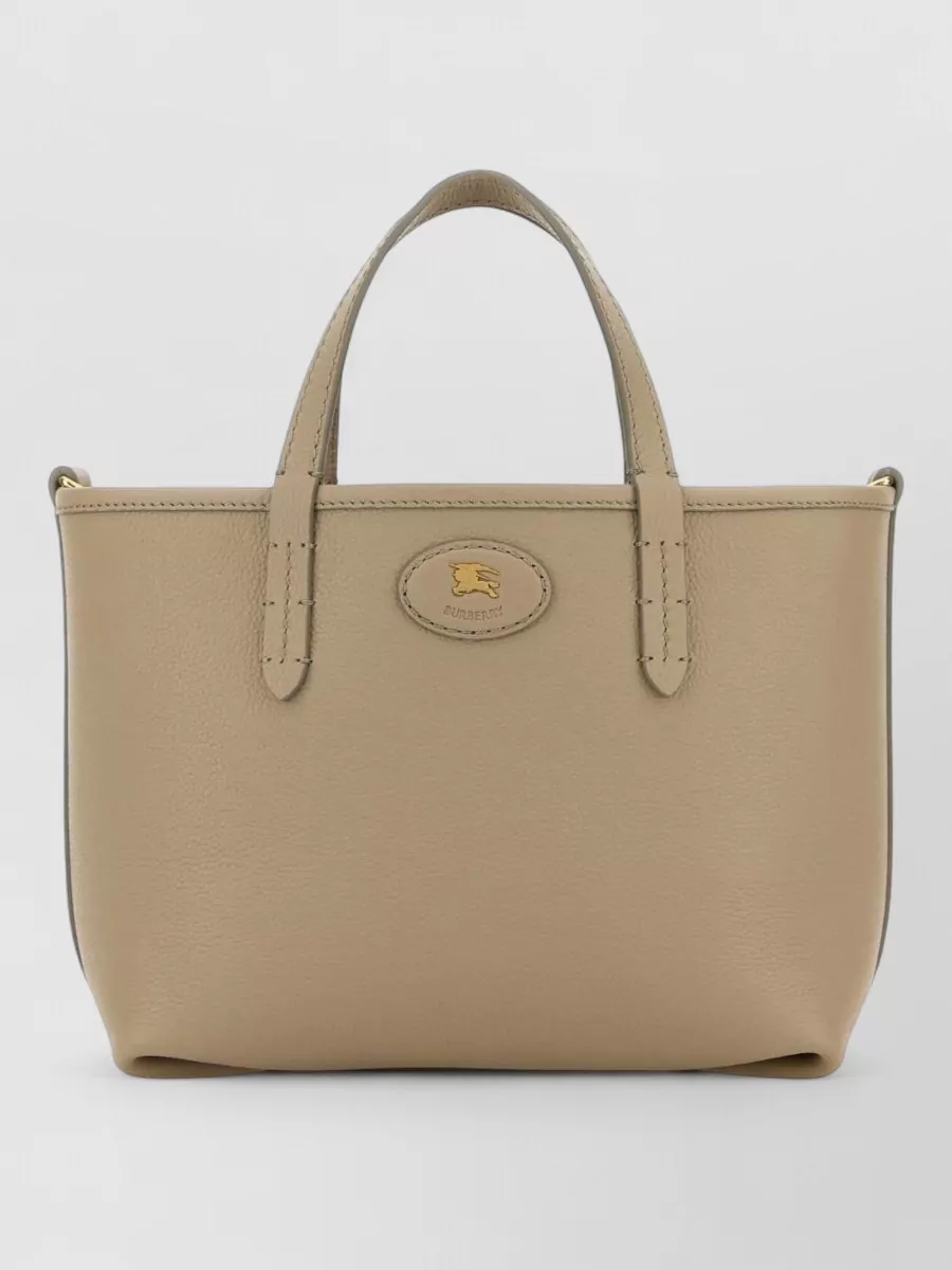 Burberry bloomsbury mini leather shoulder bag — The structured taupe top-handle tote hits the same luxury tier and tailored mood as the trench and dress, adding a neutral, logo-quiet note that keeps the outfit refined.