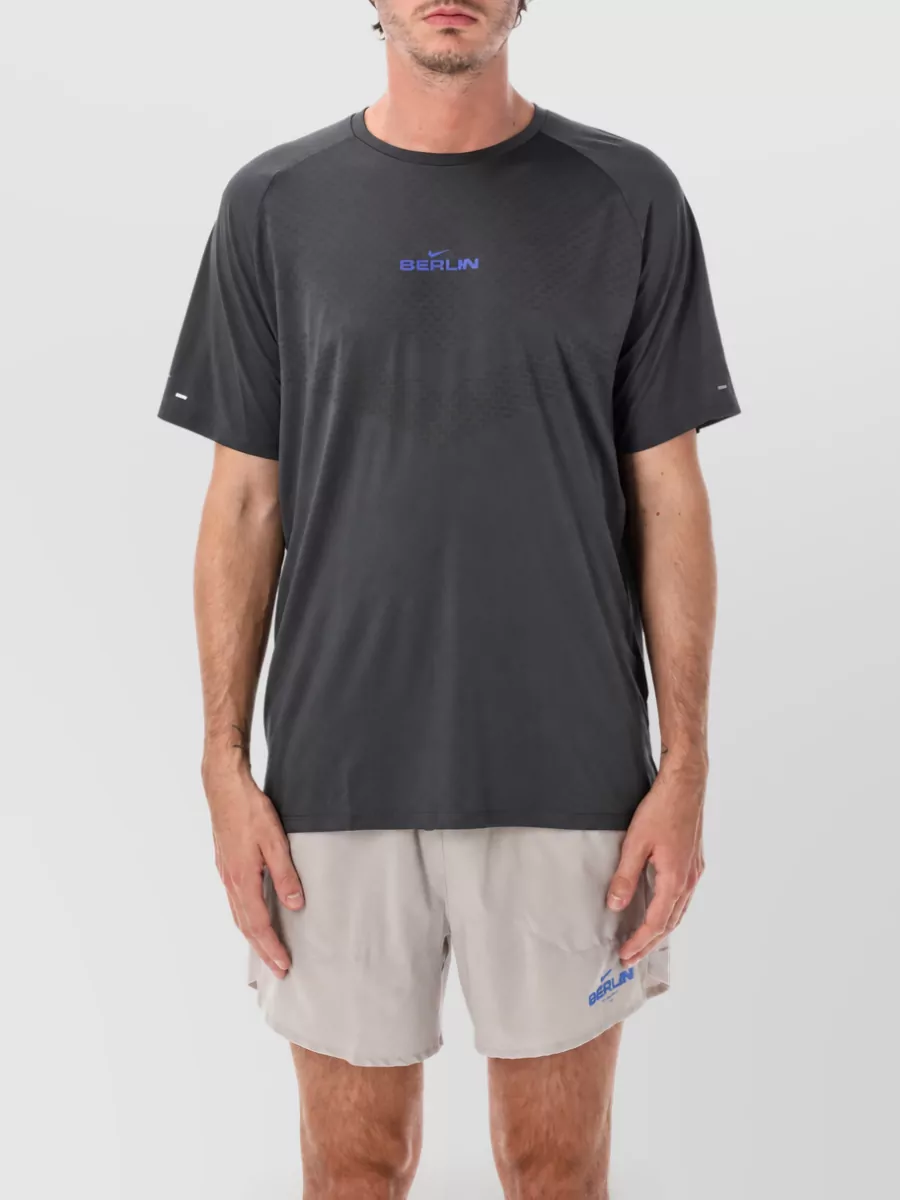Nike Graphic short-sleeve t-shirt — The charcoal Berlin performance tee mirrors the shorts' Berlin branding and blue hit while keeping the palette tight and technical, creating a coherently minimalist, run-ready set.